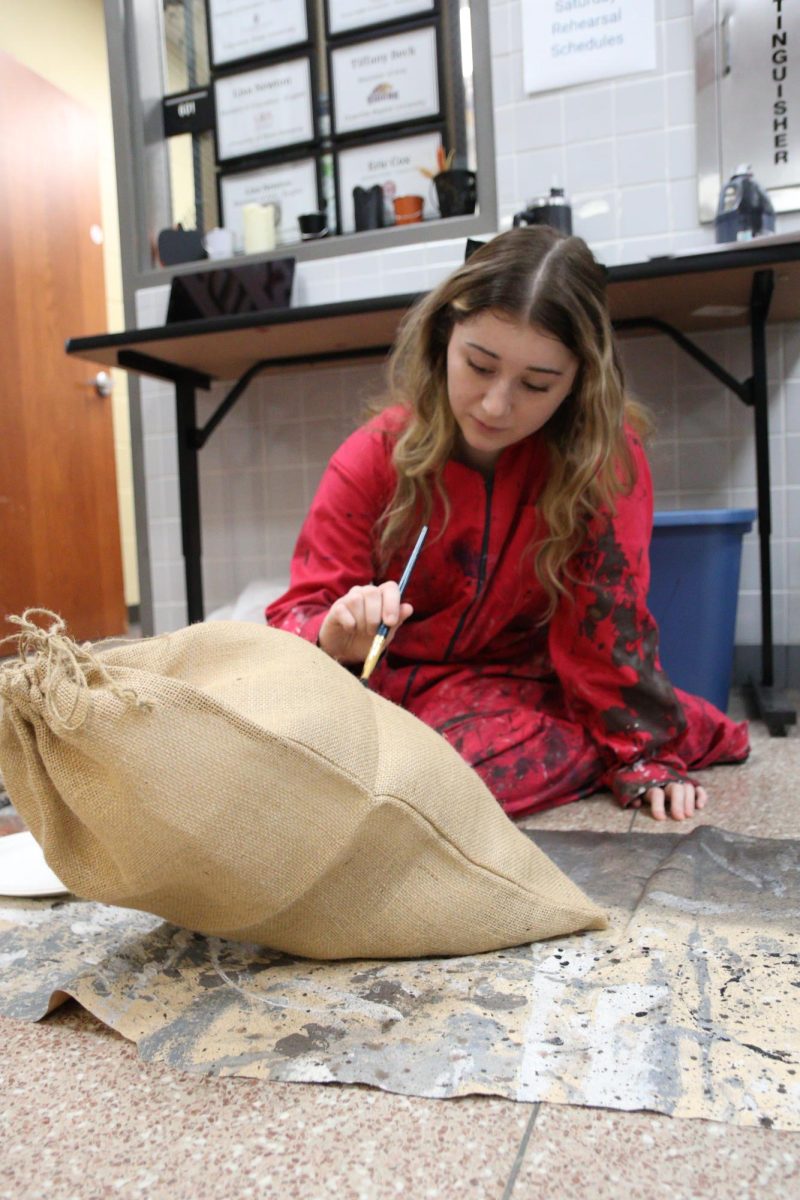 Lyla Breto (11) paints a prop for "Oklahoma!"