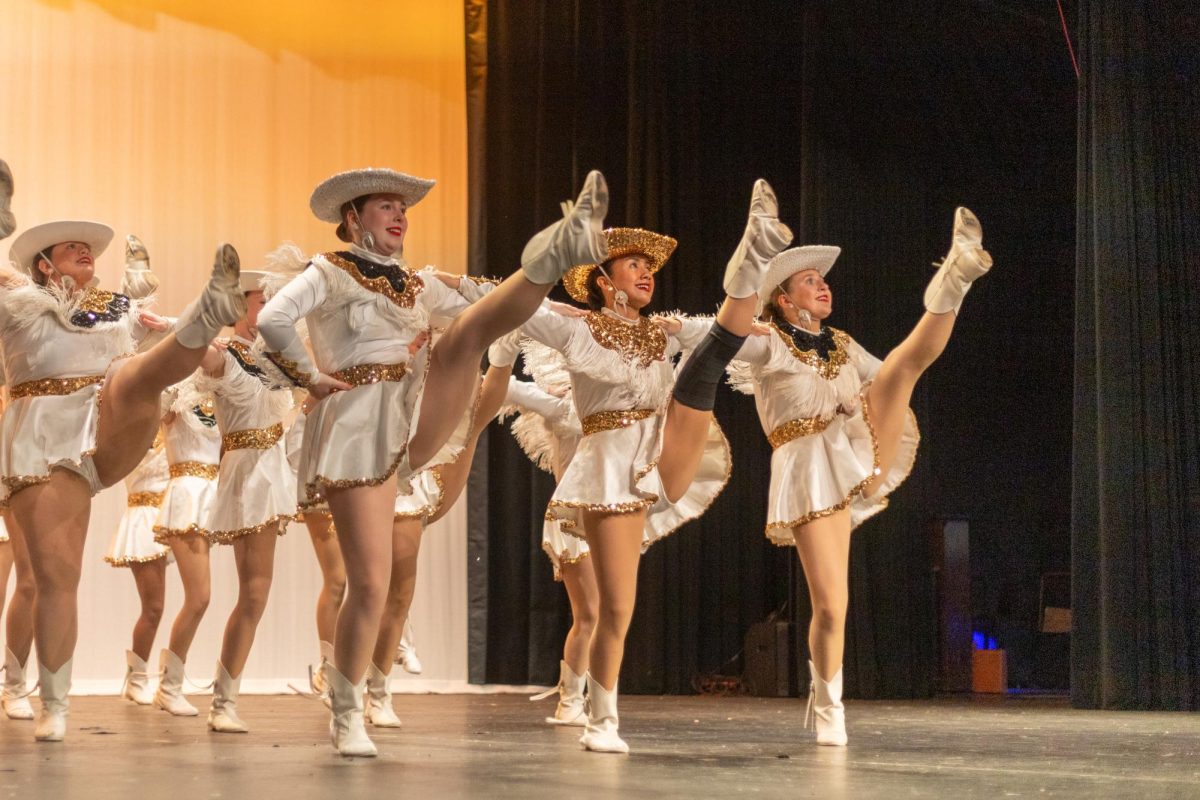 With legs extending and toes pointed, junior Sophie Douglas, (left) senior Aimee Womak, (middle) and junior Taylor Harding, (right) perform their kick line routine to Magnificent Seven.