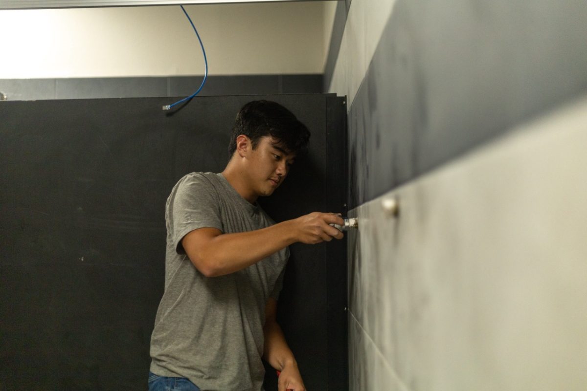 With immense focus, graduate Owen Braza repairs a faucet in the school bathroom.