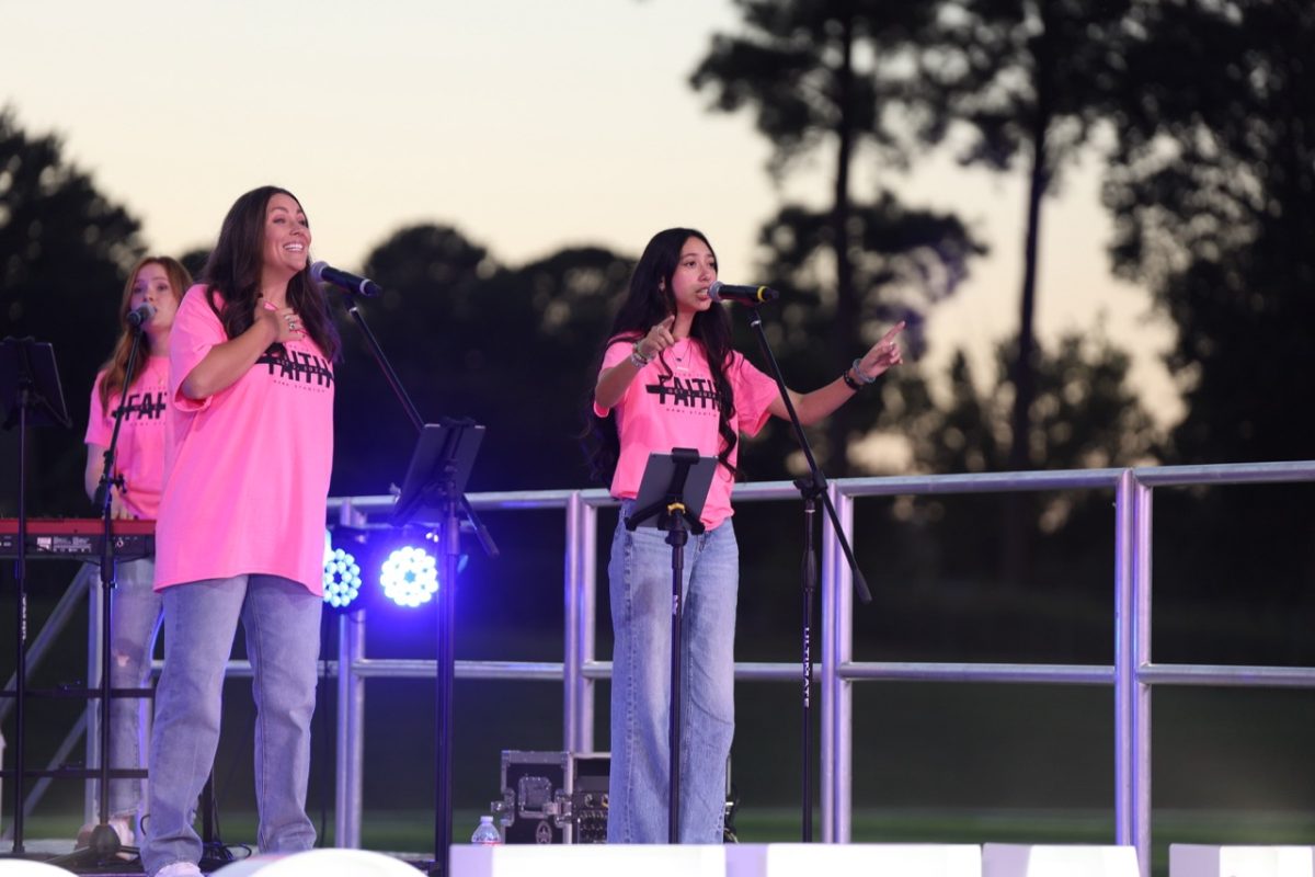While pointing to the crowd, senior Anna Grace Ballard sings on Hawk Field at last year's Fields of Faith.