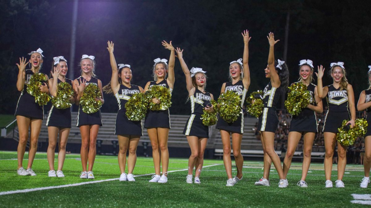 With hands raised and smiles wide, varsity cheerleaders pose with their championship rings.