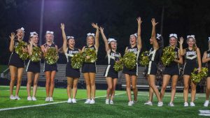 With hands raised and smiles wide, varsity cheerleaders pose with their championship rings.
