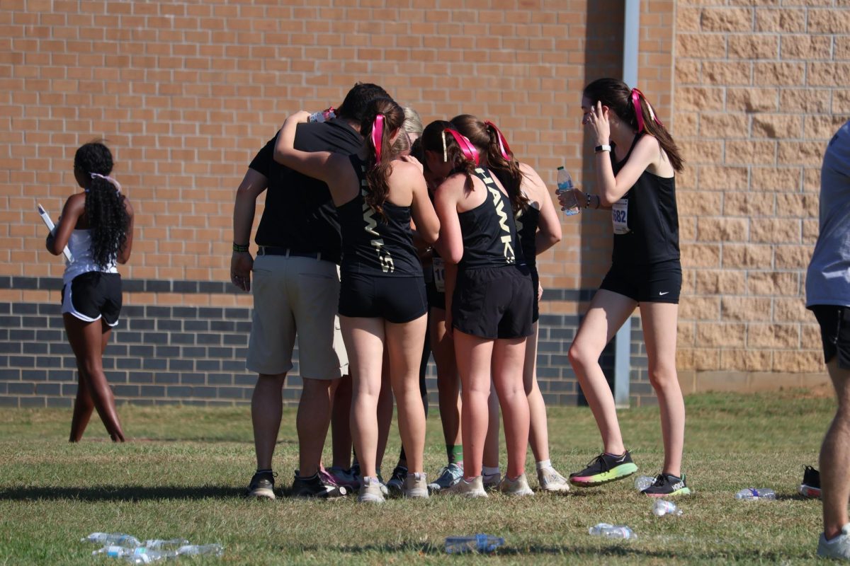 After a meet, girls cross country celebrates with their coach Larry Epstein.