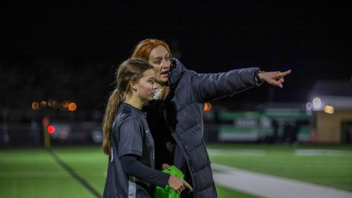 On the sideline, head coach Christa Henry coaches freshman Presley Cook on adjustments she could make to help the team in the offensive third. 
